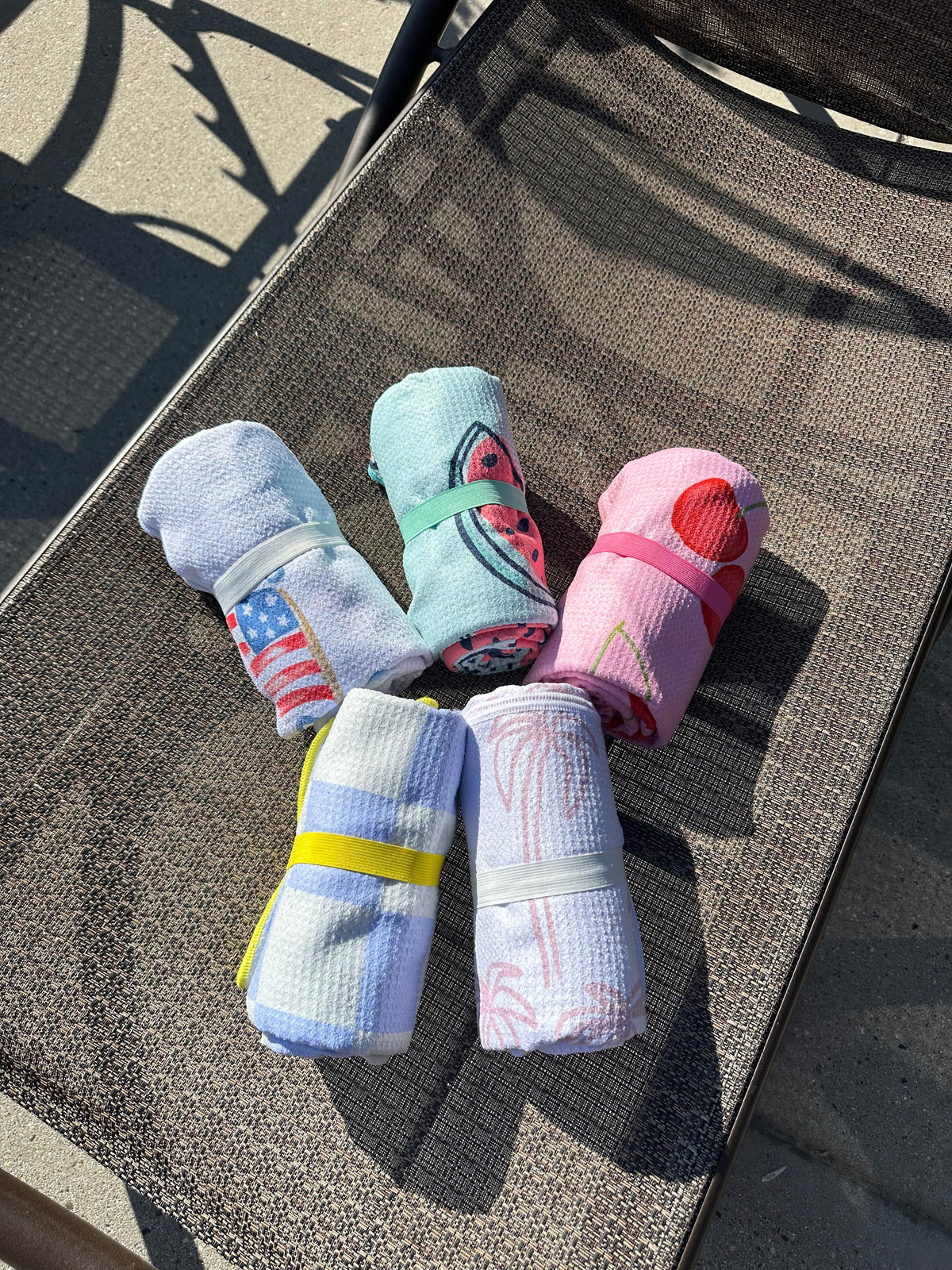 Tidy Towel reversible pool towels rolled with elastic bands on a lounge chair